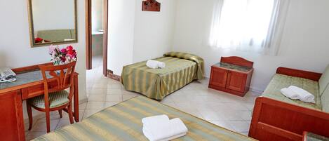 Ein Hotelzimmer mit zwei Einzelbetten, einem Holztisch mit Telefon, einem Stuhl und einem kleinen Schrank.