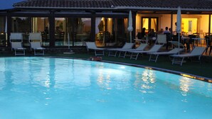 Une piscine avec des chaises longues et un espace patio couvert.