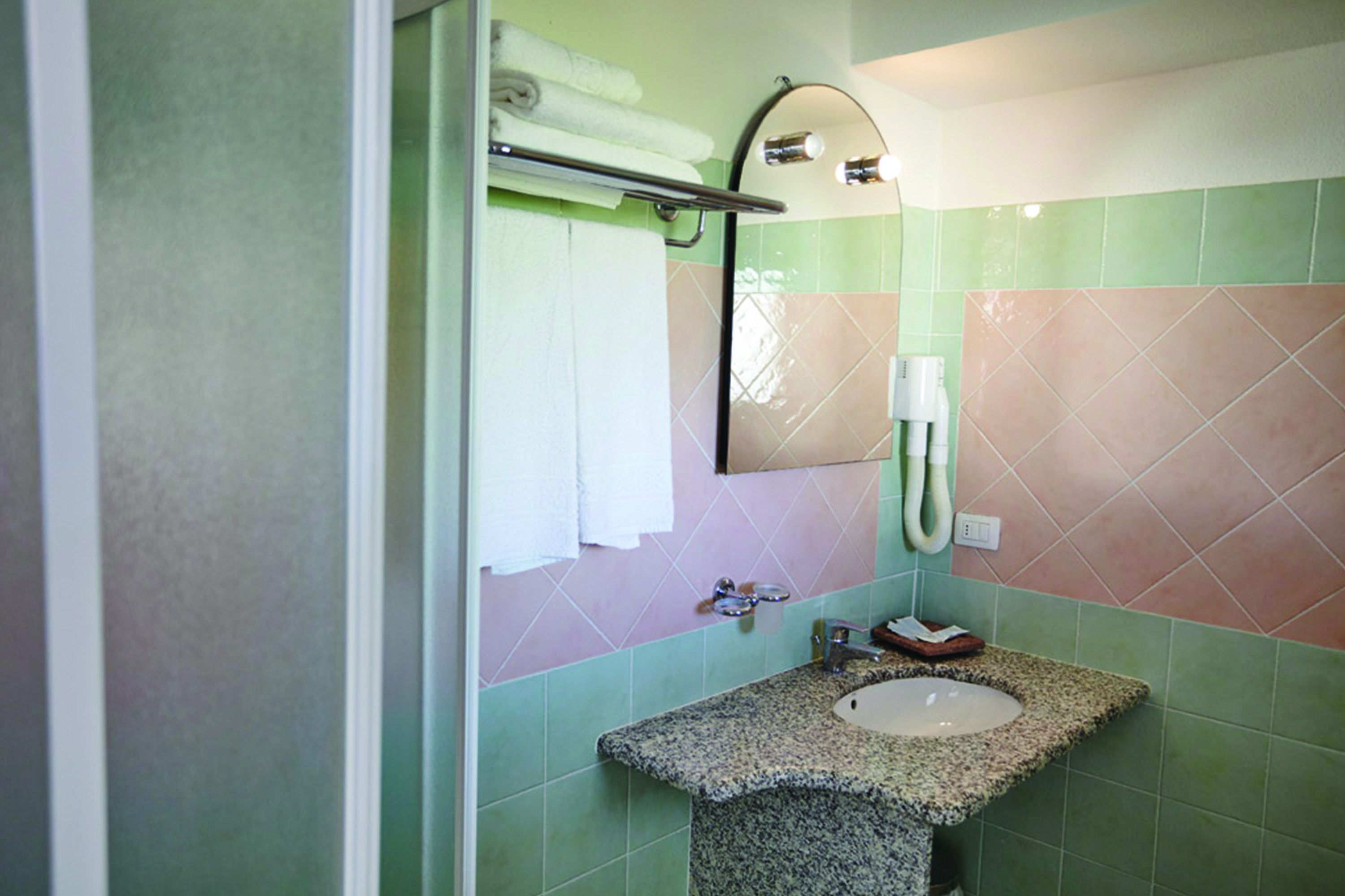 A bathroom with a granite countertop sink, a mirror, and a towel rack.