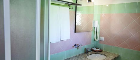 Een badkamer met een wastafel met granieten blad, een spiegel en een handdoekrek.