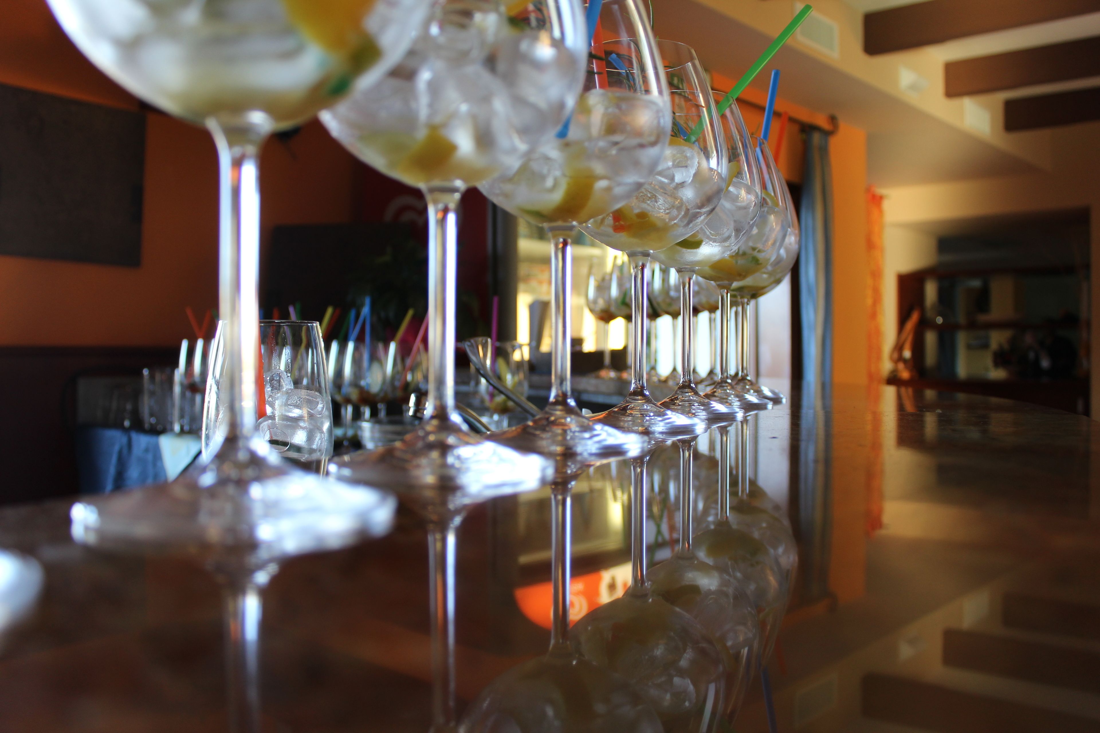 A bar with multiple glasses filled with a beverage, ice cubes, and straws.