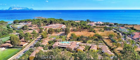 Vista aérea de una zona residencial costera con casas, piscina y una vista despejada del mar.