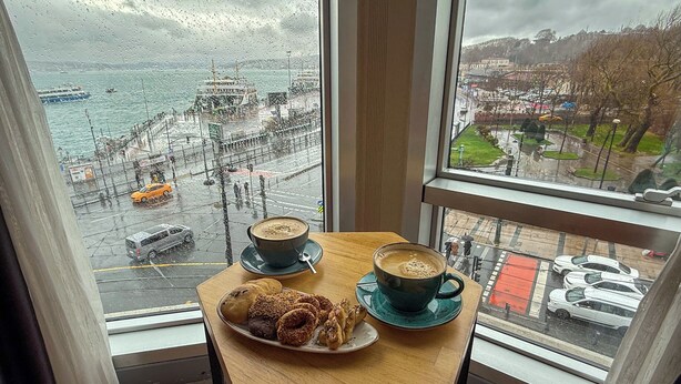 A table with a cup of coffee and pastries by a window overlooking a rainy cityscape. - Manesol Old City Bosphorus (Istanbul)