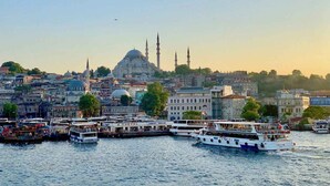 A waterfront cityscape with a prominent mosque and minarets in the background, several boats docked along the quay, and a mix of residential and commercial buildings. - Manesol Old City Bosphorus (Istanbul)