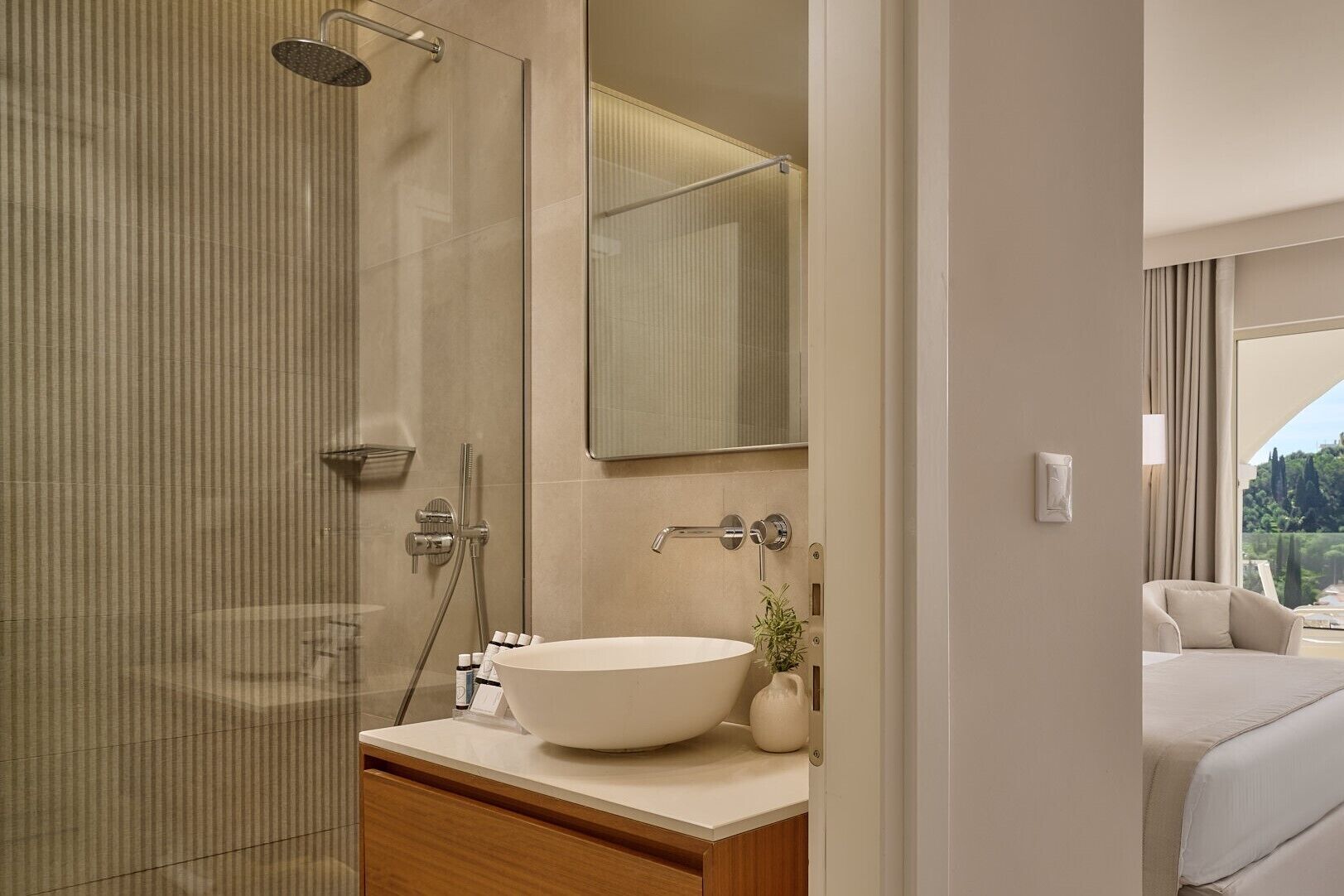 Un bagno moderno con cabina doccia in vetro, uno specchio grande e un lavandino bianco.