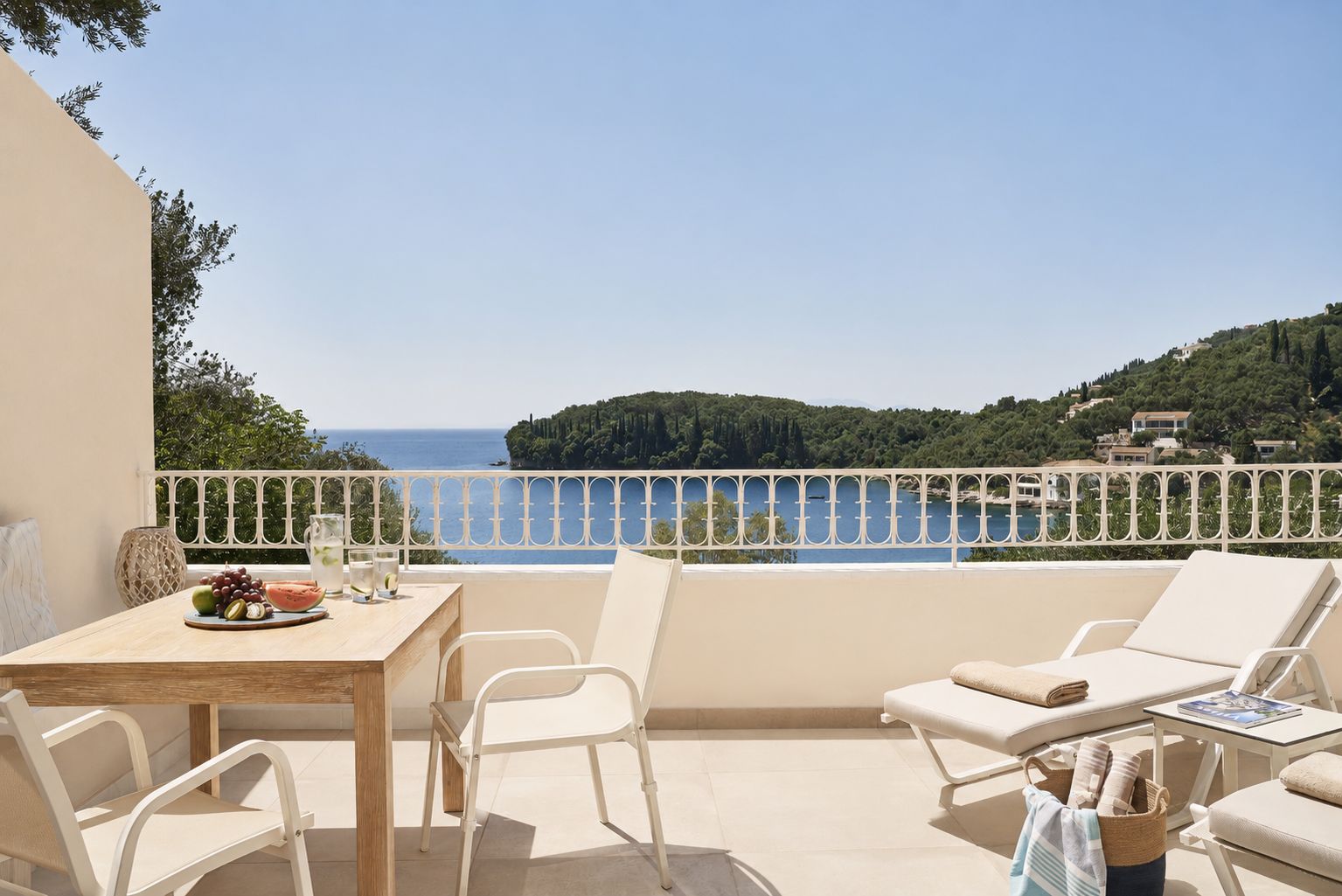 Una terraza con mesa, sillas y vistas al mar y las colinas.