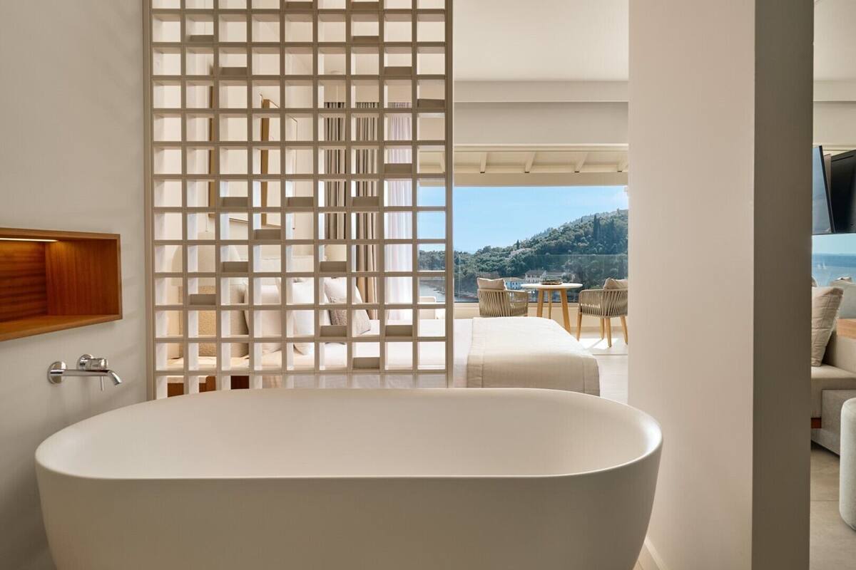 Een moderne badkamer met een vrijstaand bad, een houten medicijnkast en uitzicht op een balkon met buitenmeubilair.