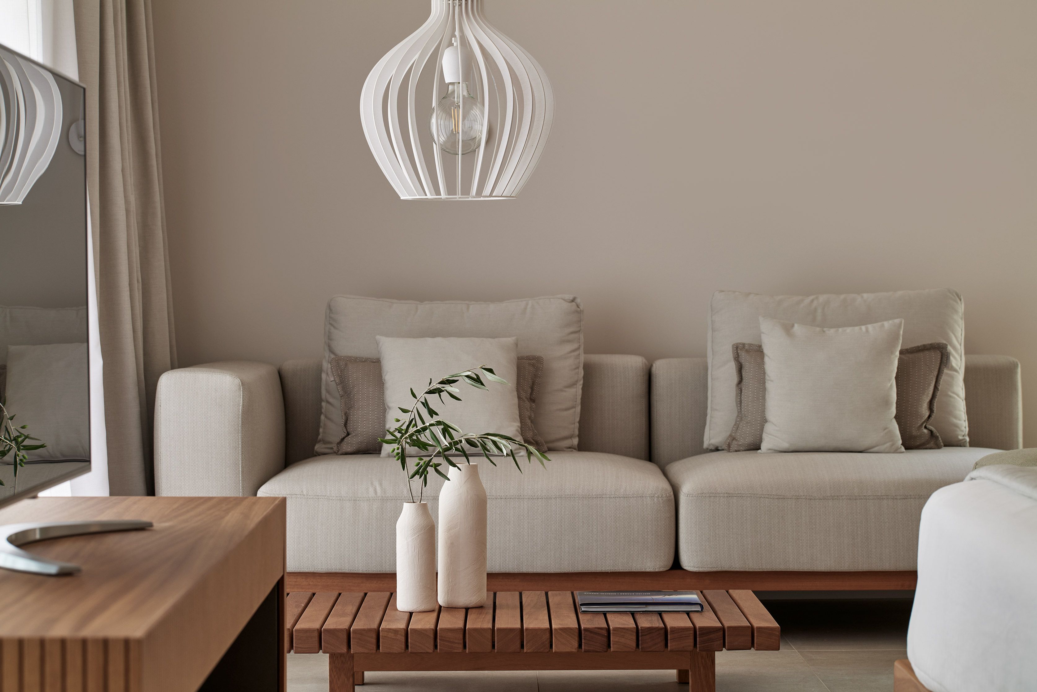 Un salon moderne avec un canapé, une table basse en bois et un luminaire suspendu.