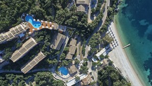 Vue aérienne d’un complexe hôtelier doté de plusieurs piscines, d’une plage et d’une végétation luxuriante.