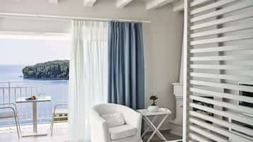 A balcony with a white chair, a small table with a blue plate, and a potted plant.