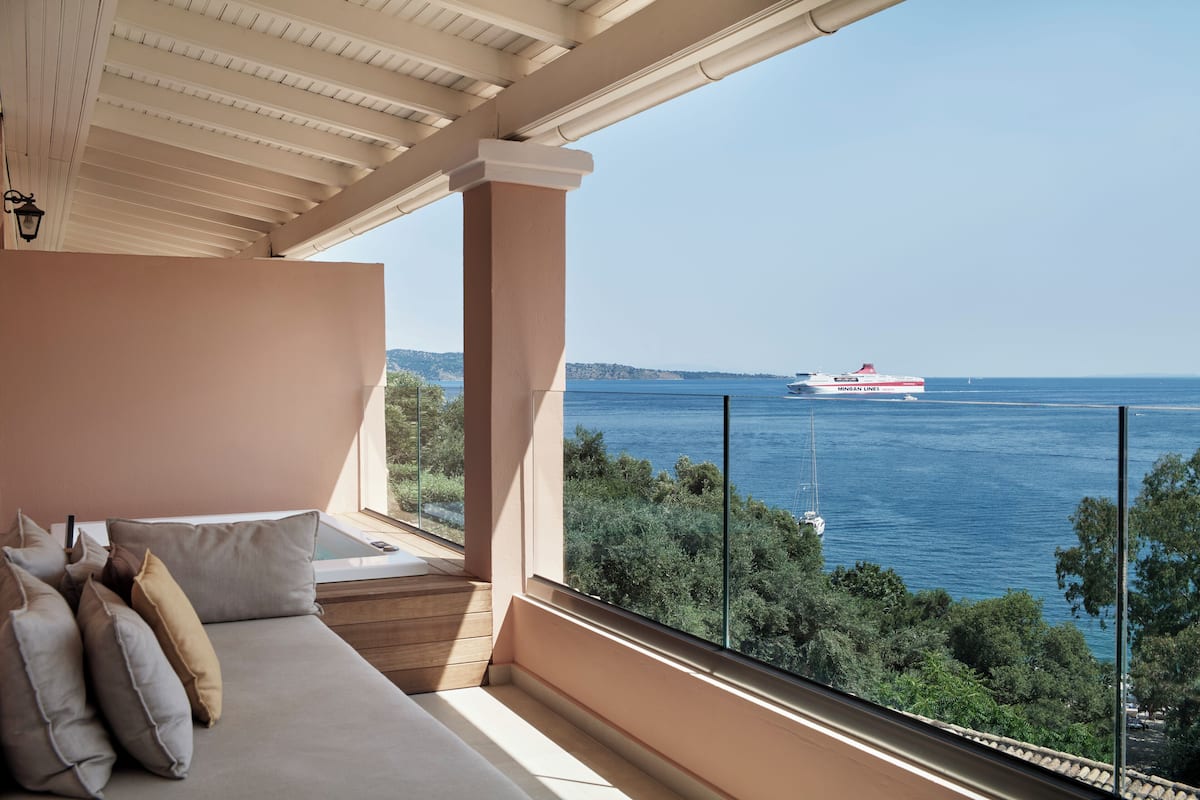 Een balkon met uitzicht op zee en een cruiseschip in de verte.