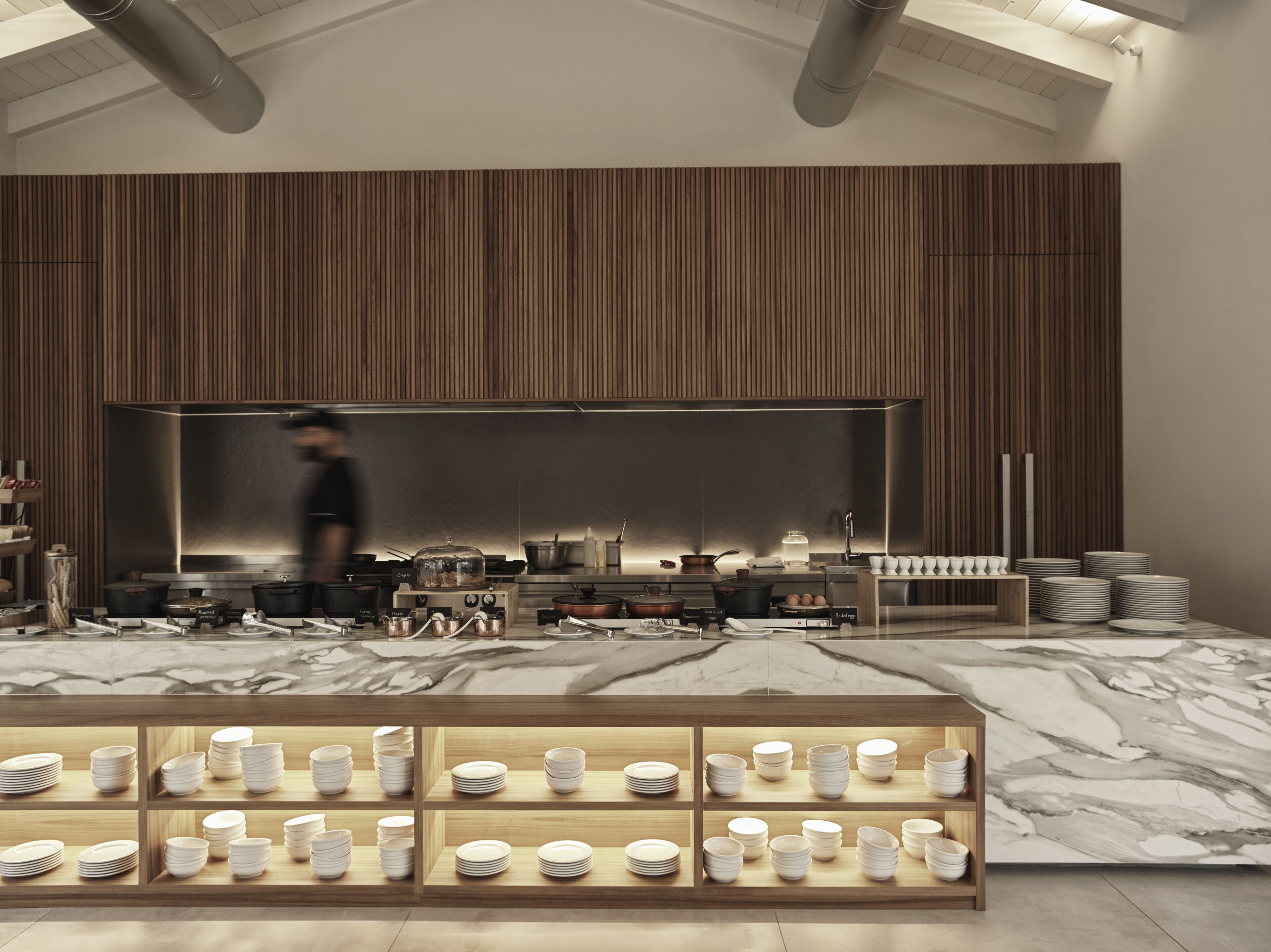 Una cocina moderna con una isla central grande, paneles de madera en las paredes y encimera de mármol.