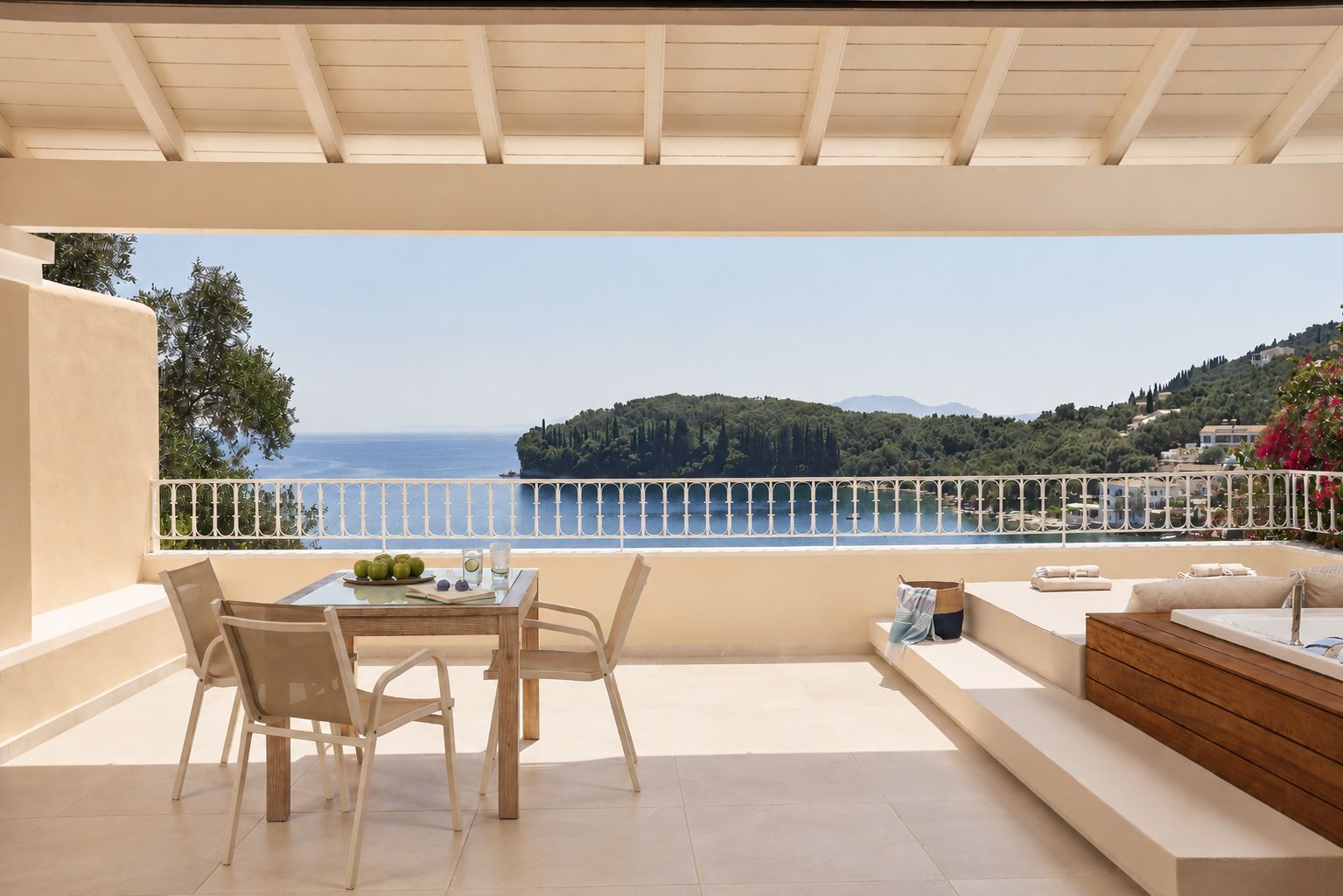 Un balcón con vistas al mar y las colinas, una mesa con sillas y un sofá.