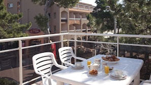 A balcony with a table set for breakfast, white chairs, and a view of a building with a sign reading "GRAND HOTEL LIDO". - Résidence du Lido (Argelès-sur-Mer)