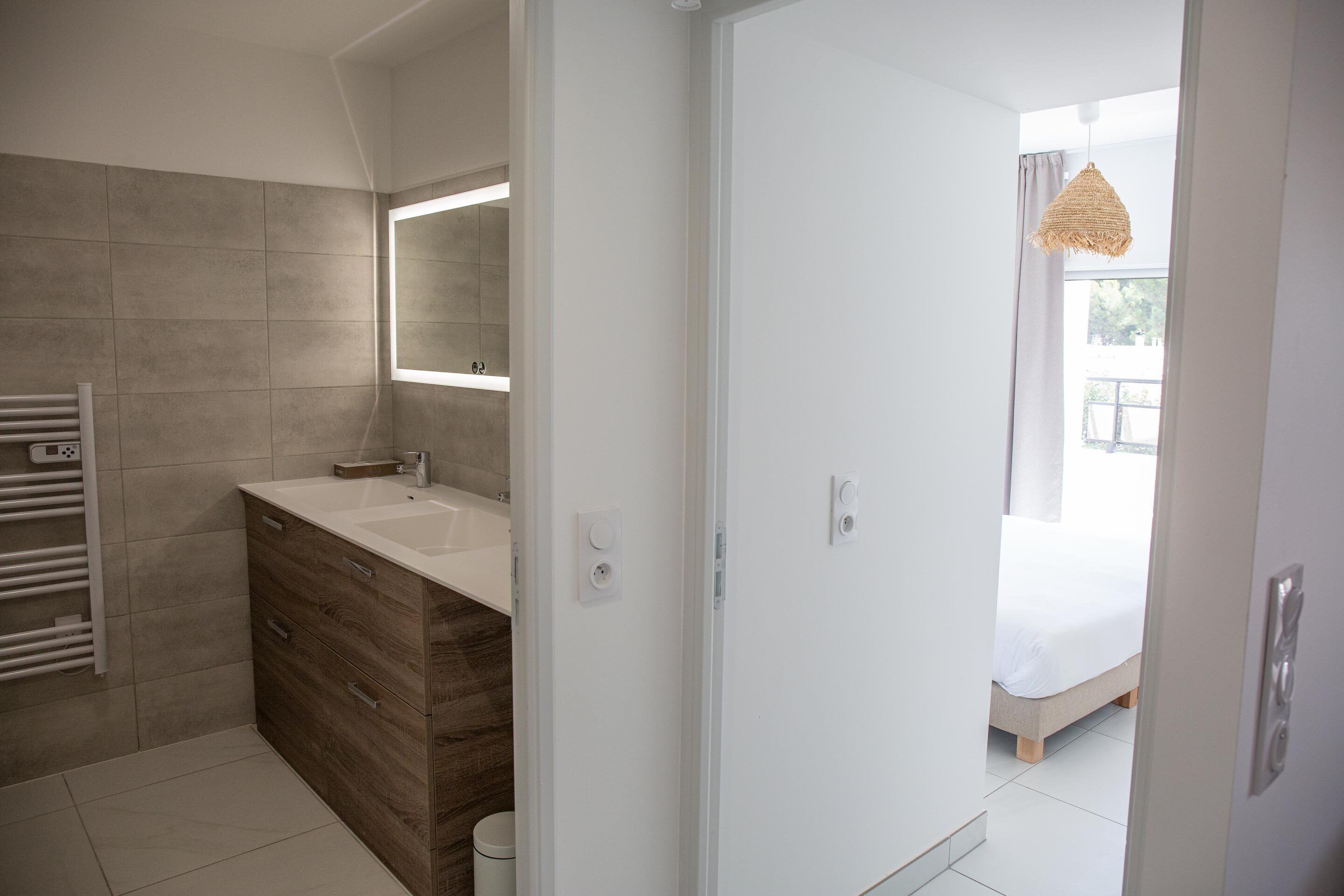 Een moderne badkamer met een houten wastafelmeubel, een grote spiegel en een witte wasbak.