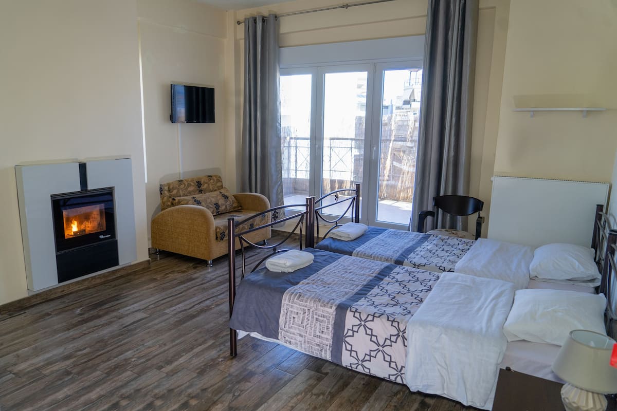 Ein Hotelzimmer mit zwei Betten, einem Kamin, einer Couch und einem Balkon mit Blick.