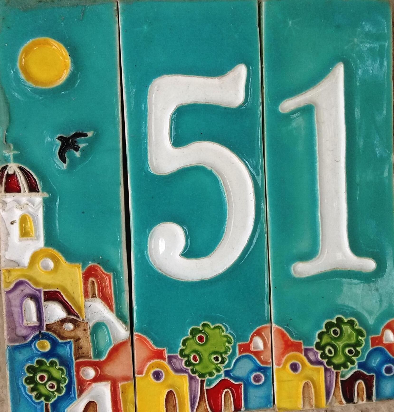 Une mosaïque aux couleurs vives représentant le chiffre 51, une église stylisée et des maisons.