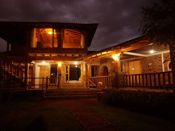 A two-story wooden house with a porch, steps leading to the entrance, and a brick pathway. - Hacienda Jimenita Wildlife Reserve (Pifo)