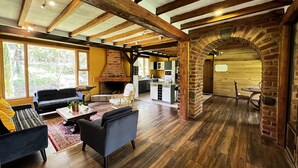 Un amplio espacio de sala de estar con chimenea, vigas de madera y una cocina al fondo.