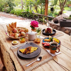 A breakfast table set outdoors with bread, pastries, fruit, and beverages. - Hacienda Jimenita Wildlife Reserve (Pifo)
