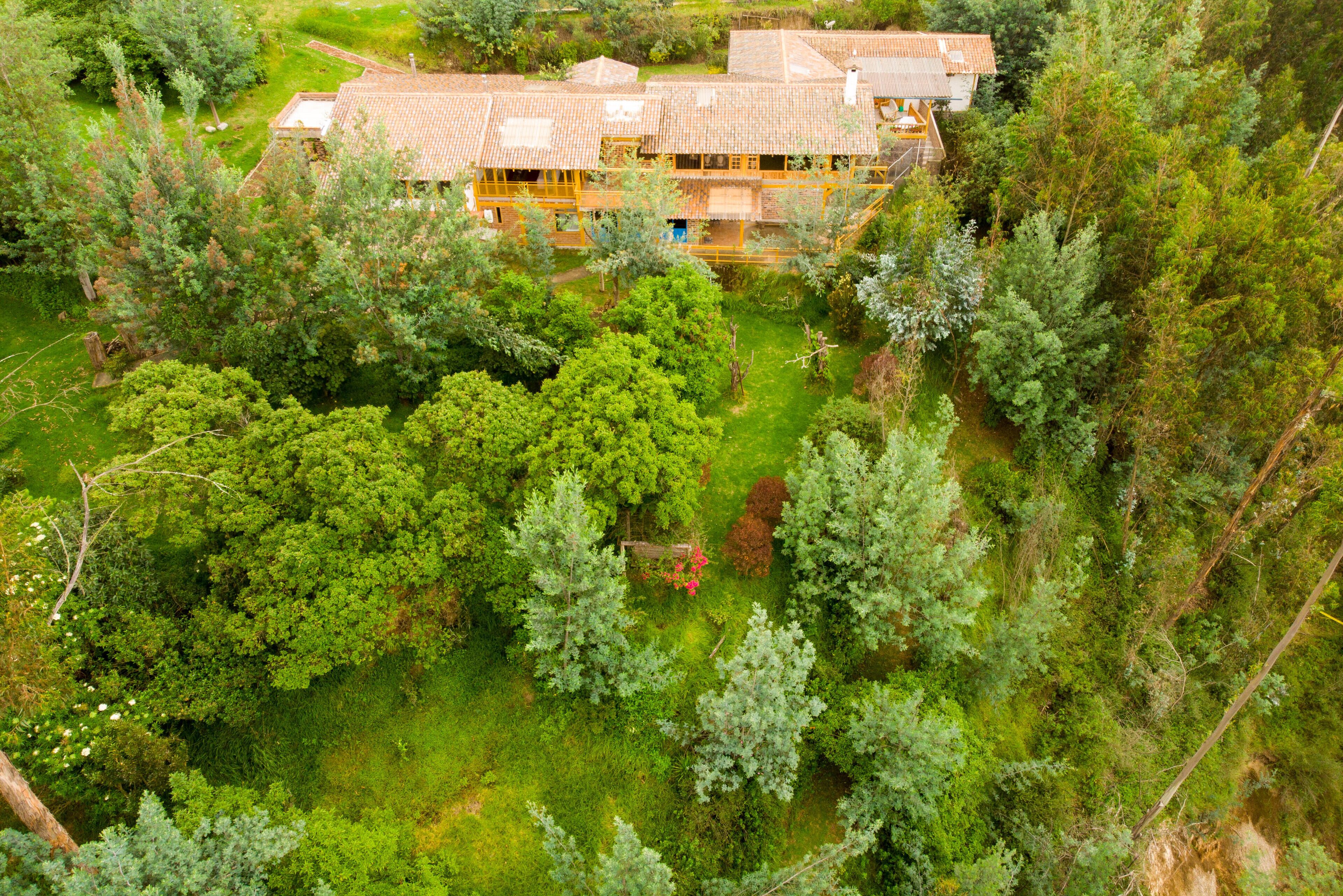 A large, multi-story building surrounded by dense greenery, with a well-maintained lawn and several trees.