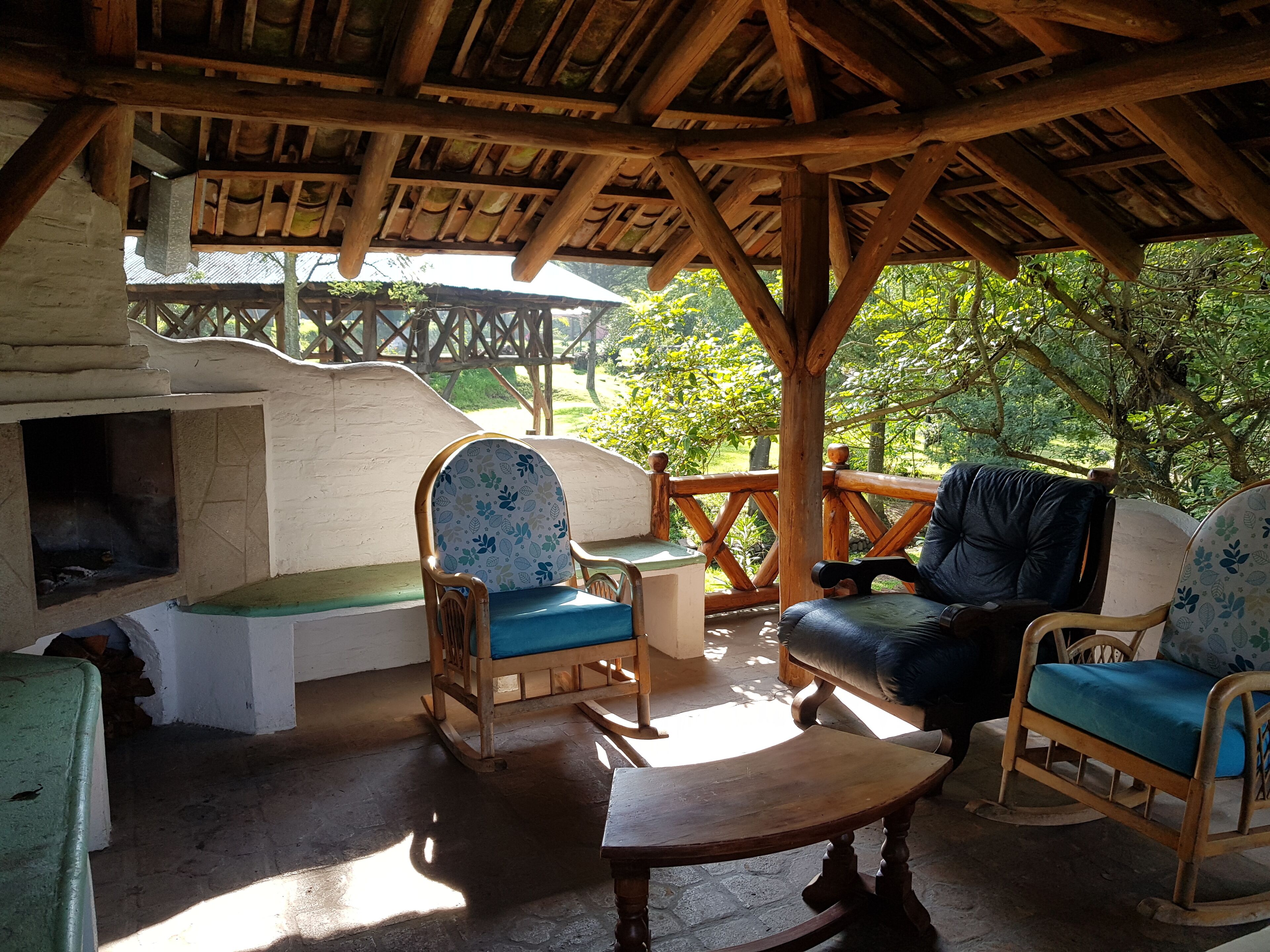 Un espace extérieur aménagé dans un style rustique, avec des meubles en bois et une cheminée en pierre.