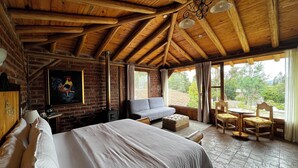 Una habitación rústica de madera con una cama grande, un sofá y un comedor con sillas.