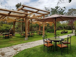 An outdoor patio area with wooden pergolas, tables, and chairs. - Hacienda Jimenita Wildlife Reserve (Pifo)