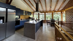 Una cocina moderna con una isla central, electrodomésticos integrados y amplios ventanales con vistas al exterior.