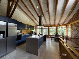 Una cocina moderna con una isla central, electrodomésticos integrados y amplios ventanales con vistas al exterior.