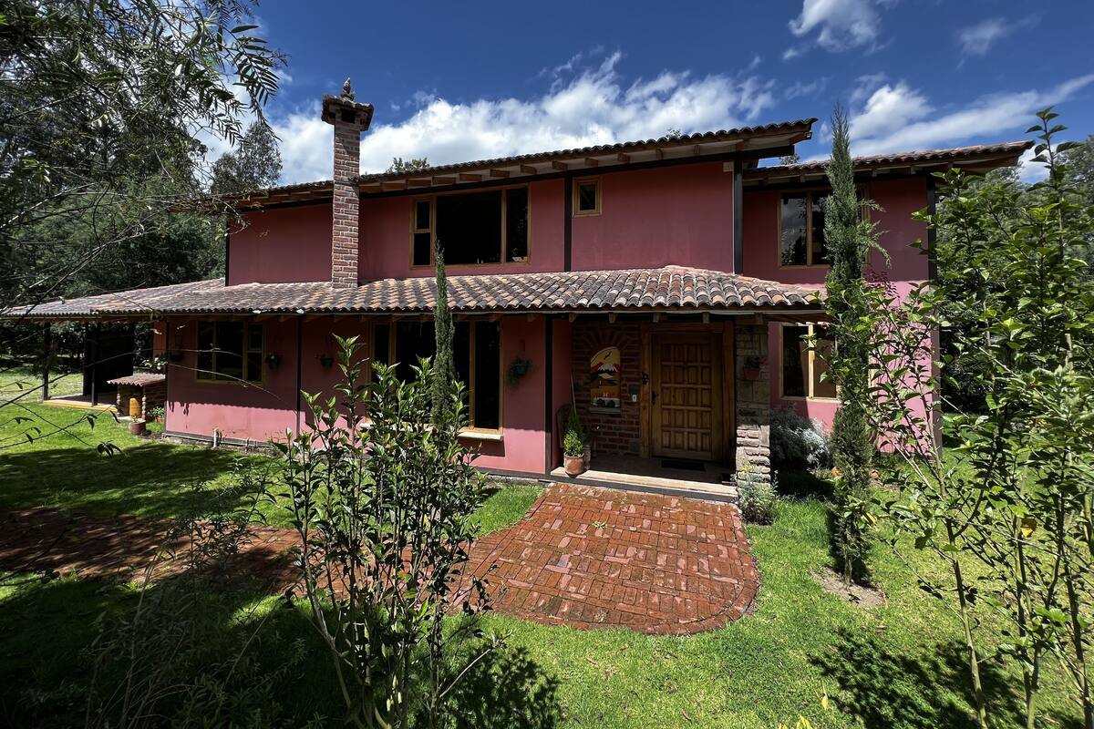 A two-story house with a tiled roof, a brick chimney, and a front porch.