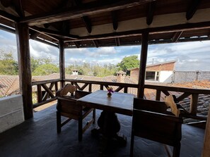 A wooden deck with a table and chairs, overlooking a residential area with tiled roofs and trees. - Hacienda Jimenita Wildlife Reserve (Pifo)