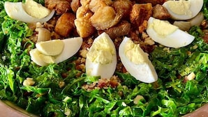A buffet with a variety of dishes including greens, meat, and eggs.