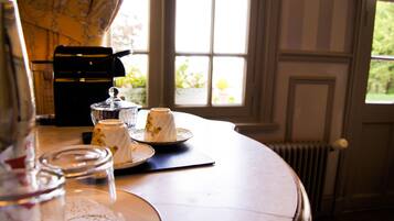 Une table avec une machine à café, une théière, des tasses et un bocal en verre.