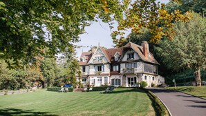 Een groot, historisch huis met een verzorgd gazon en een oprit.