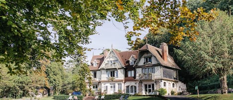 Een groot, historisch huis met een verzorgd gazon en een oprit.