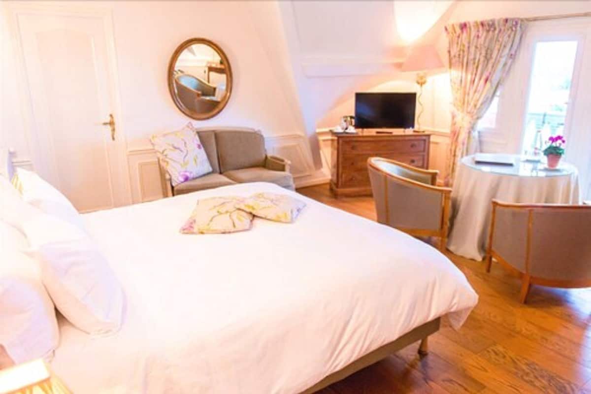 Une chambre à coucher comprenant un lit, une commode, un téléviseur, une chaise et une petite table.