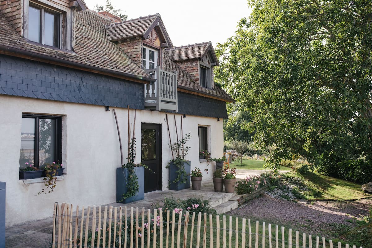 Une maison à deux étages avec un balcon, des plantes en pot et une clôture en bois.