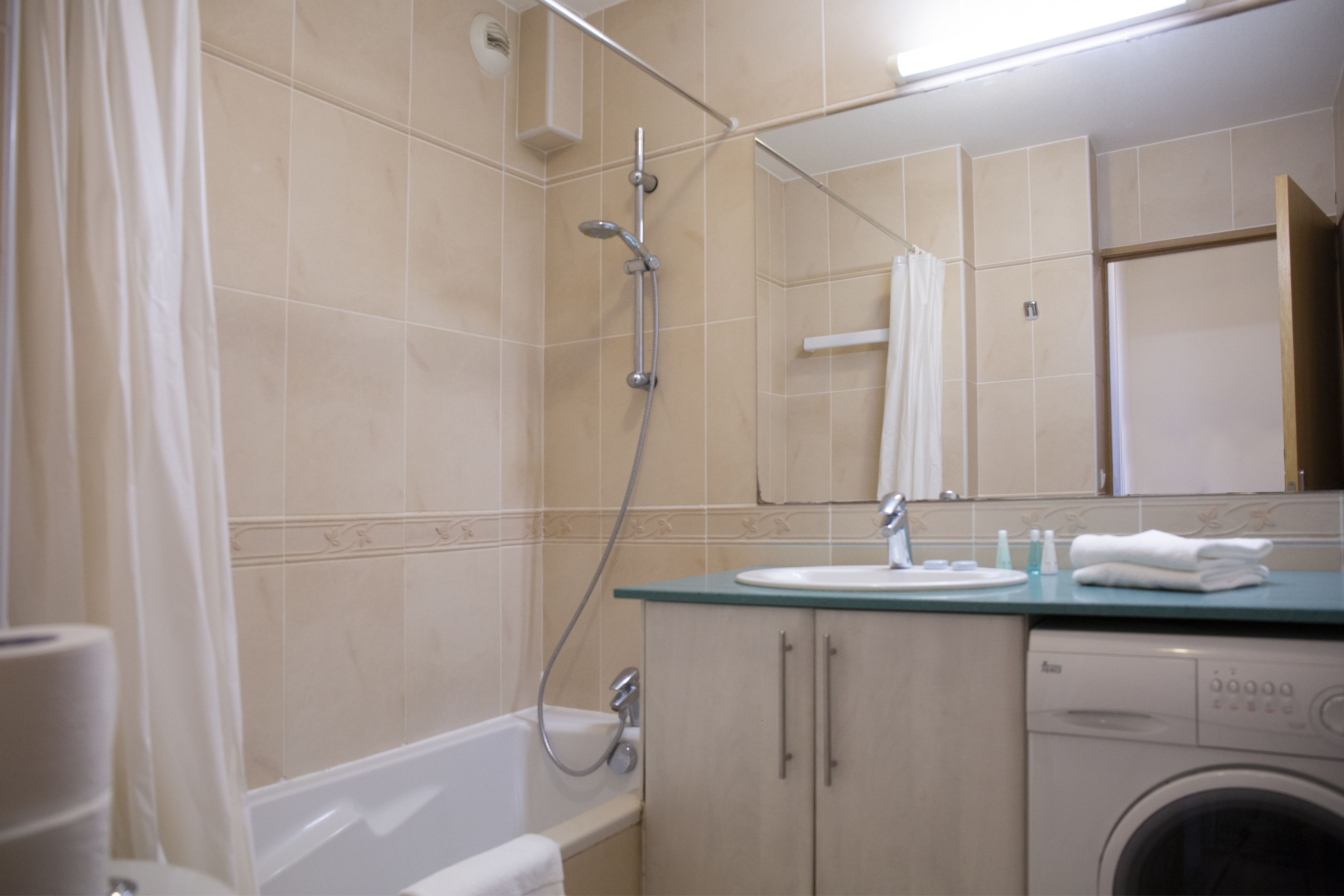 A bathroom with a bathtub, a shower, a sink, and a washing machine.