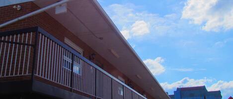 Un hotel con balcón, un cartel que indica la oficina de un motel y un letrero de restaurante visible al fondo.