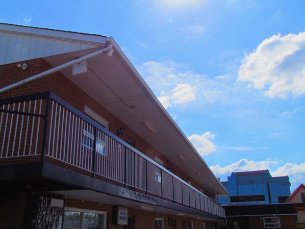 A hotel with a balcony, a sign indicating a motel office, and a visible restaurant sign in the background. - The Falls A Family Lodge (Niagara Falls)
