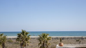 Une plage bordée de palmiers, une étendue de sable et un ciel bleu azur.