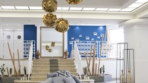 Un intérieur moderne avec un fauteuil en forme de poire à motifs, un escalier et des éléments décoratifs tels que des sphères suspendues et des œuvres d’art mural.