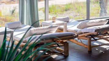 Relax in a serene spa setting with a lounge chair arrangement, a small table, and a peaceful natural view.