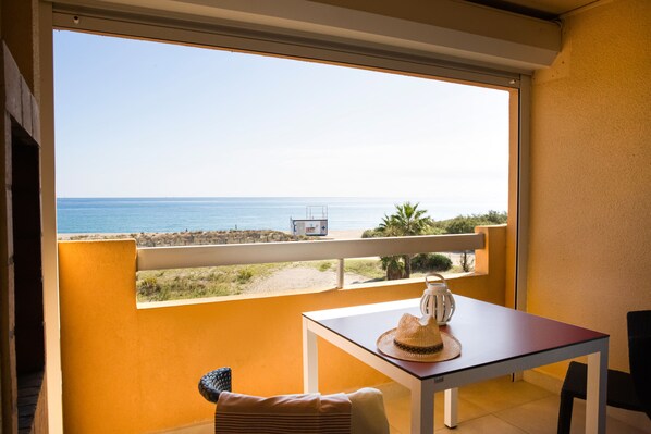 Un balcon avec vue sur la mer, une table agrémentée d’un objet décoratif et une chaise.