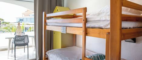 A bunk bed with a sign on the mattress, a chair, and a view of the outside.