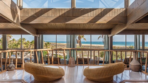 Un balcon spacieux, doté de meubles en osier et offrant une vue sur la plage.