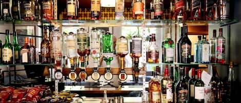 A bar with multiple shelves of various liquor bottles, a cash register, and snacks.