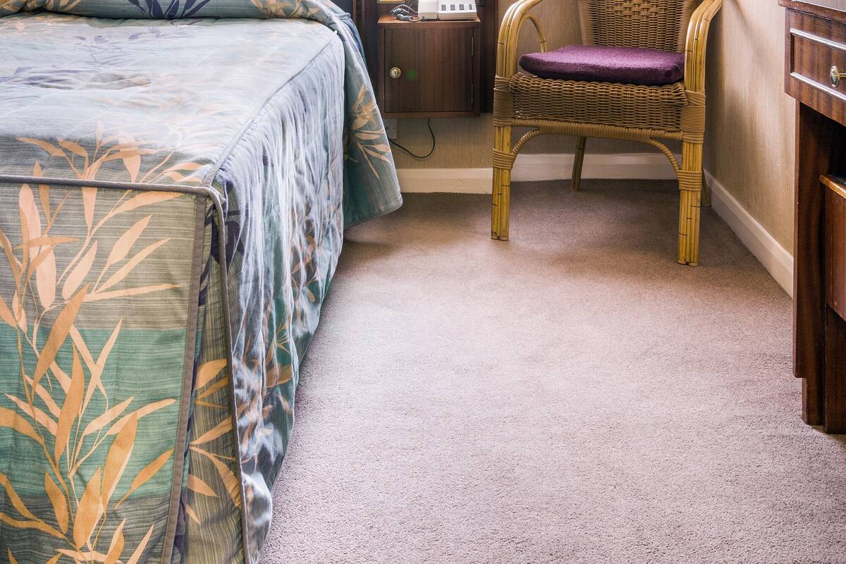 A hotel room with a bed, a chair, a desk, and a window with curtains.