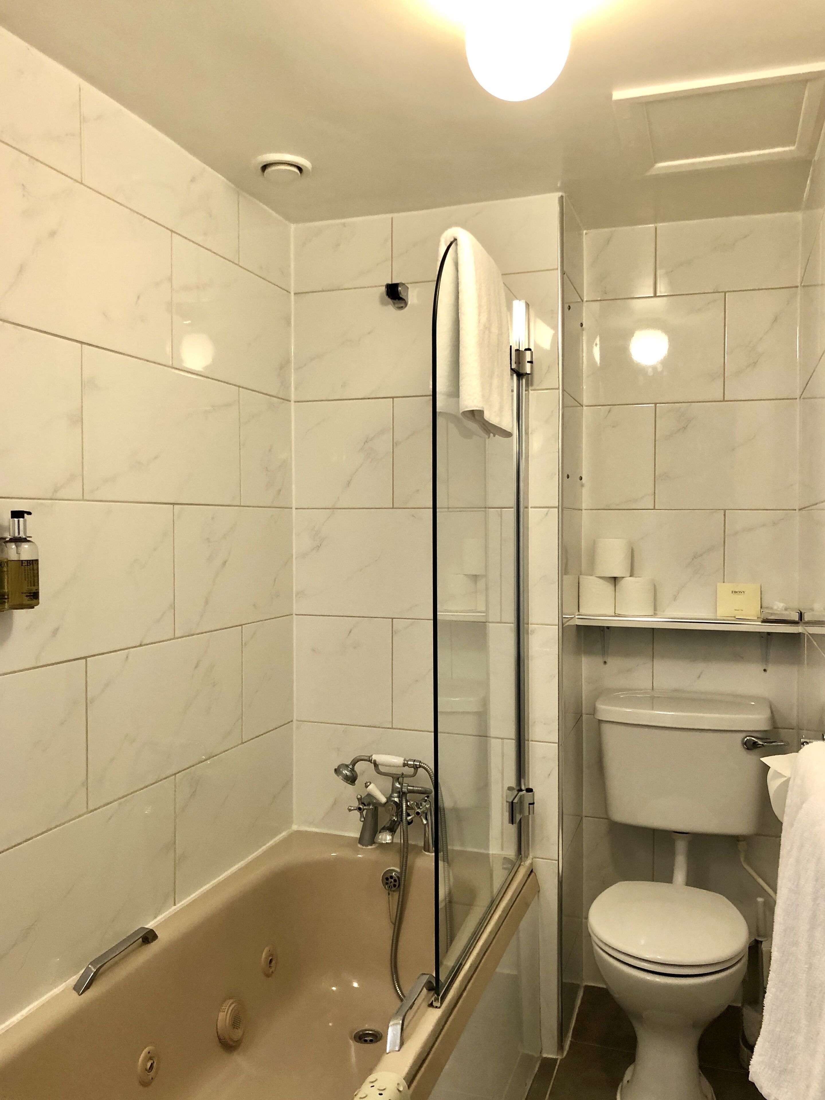 Un baño moderno con bañera, ducha con mampara de vidrio, inodoro y azulejos de mármol.